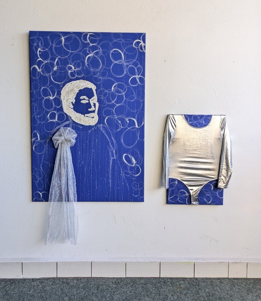 Zwei Bilder hängen an einer Wand. Farben Königsblau und Silber.